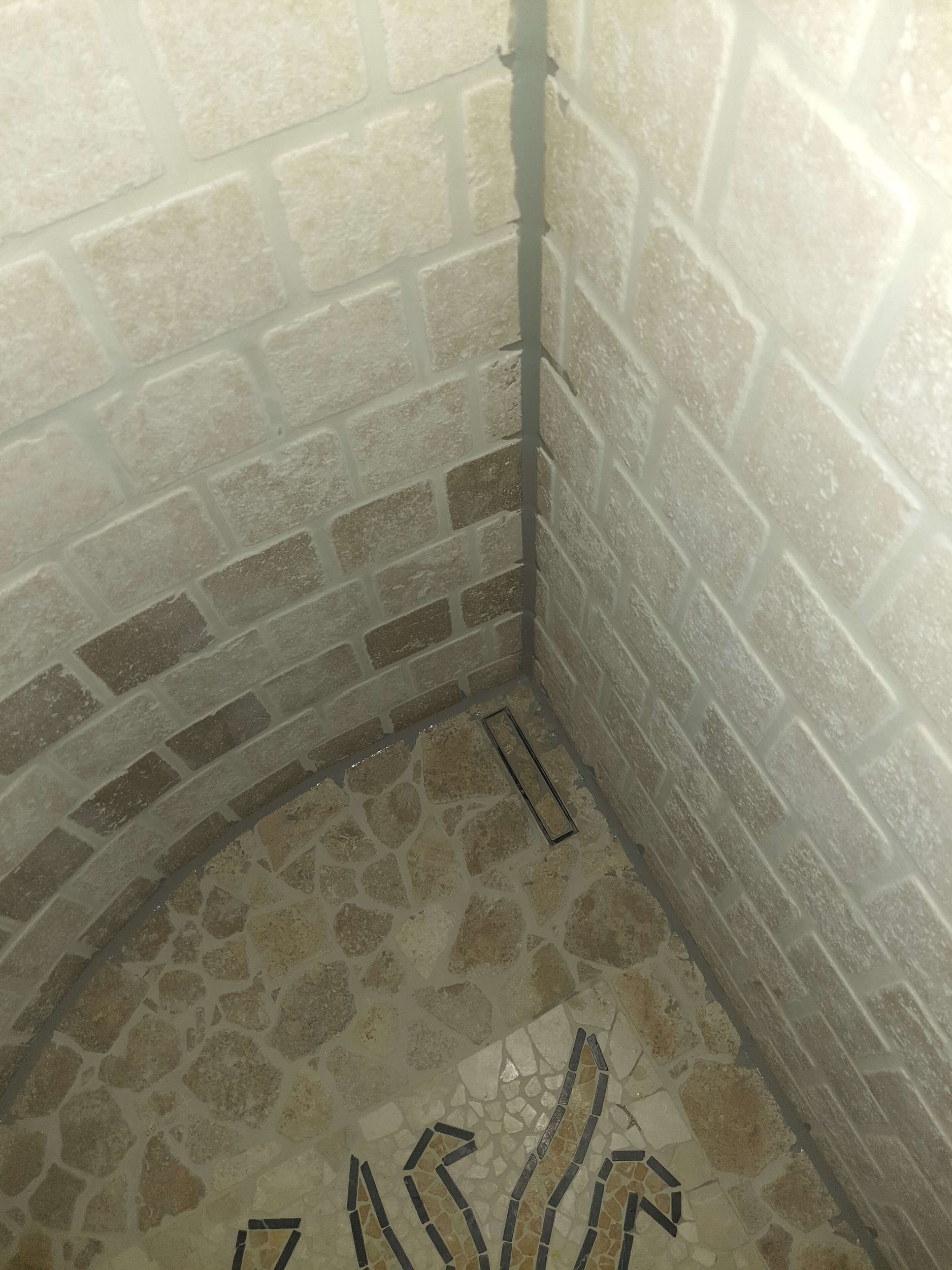 Eine Badezimmerecke mit einer Ziegelwand und einem Mosaikboden.