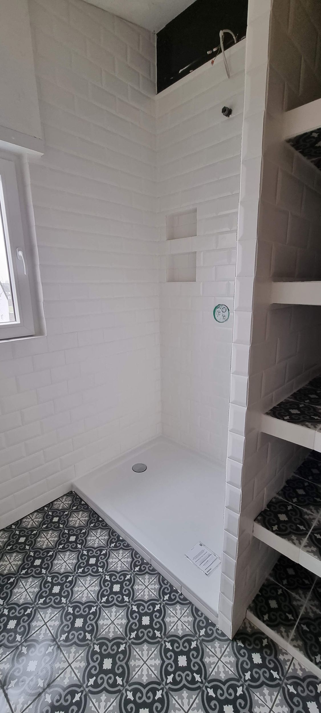 Ein Badezimmer mit ebenerdiger Dusche und Fenster.