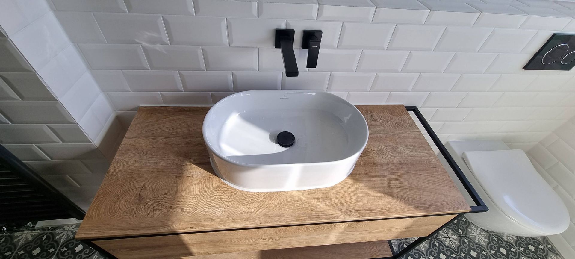 In einem Badezimmer steht ein weißes Waschbecken auf einer Holzablage.