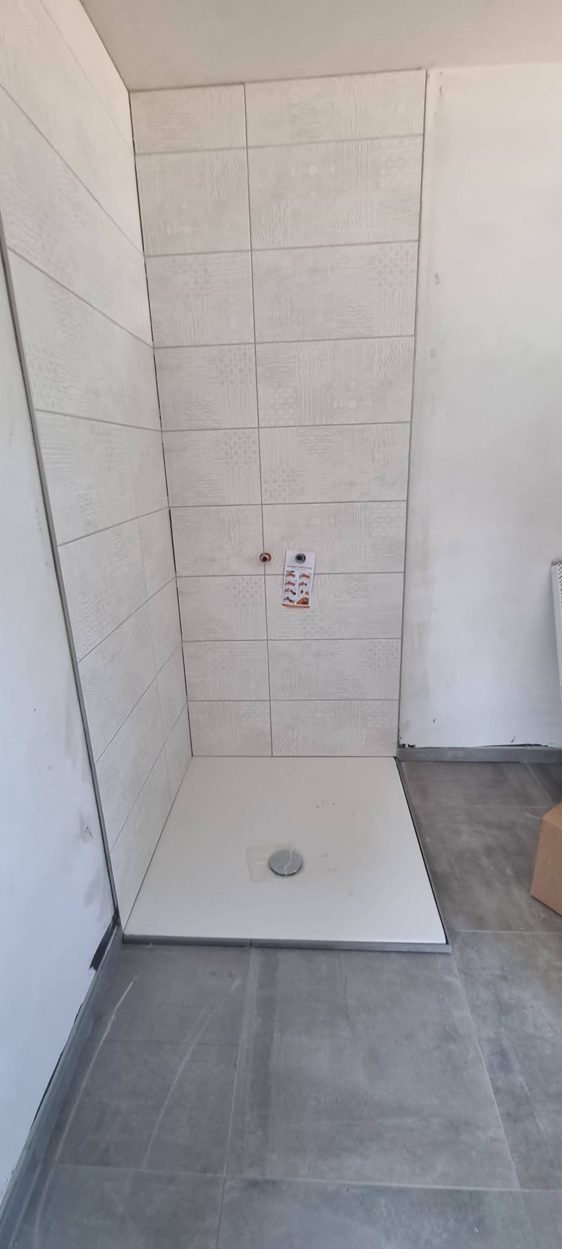 Ein Badezimmer mit ebenerdiger Dusche und gefliester Wand.