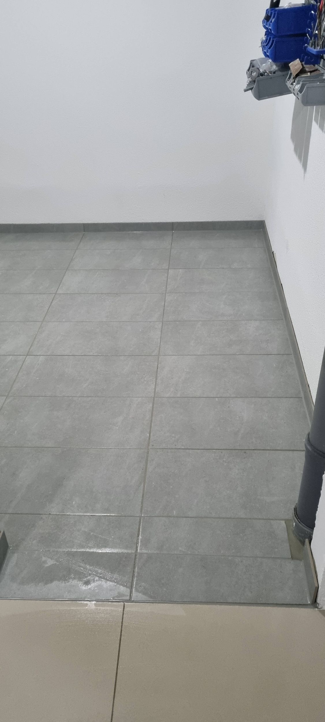 Ein Raum mit gefliestem Boden und weißer Wand.