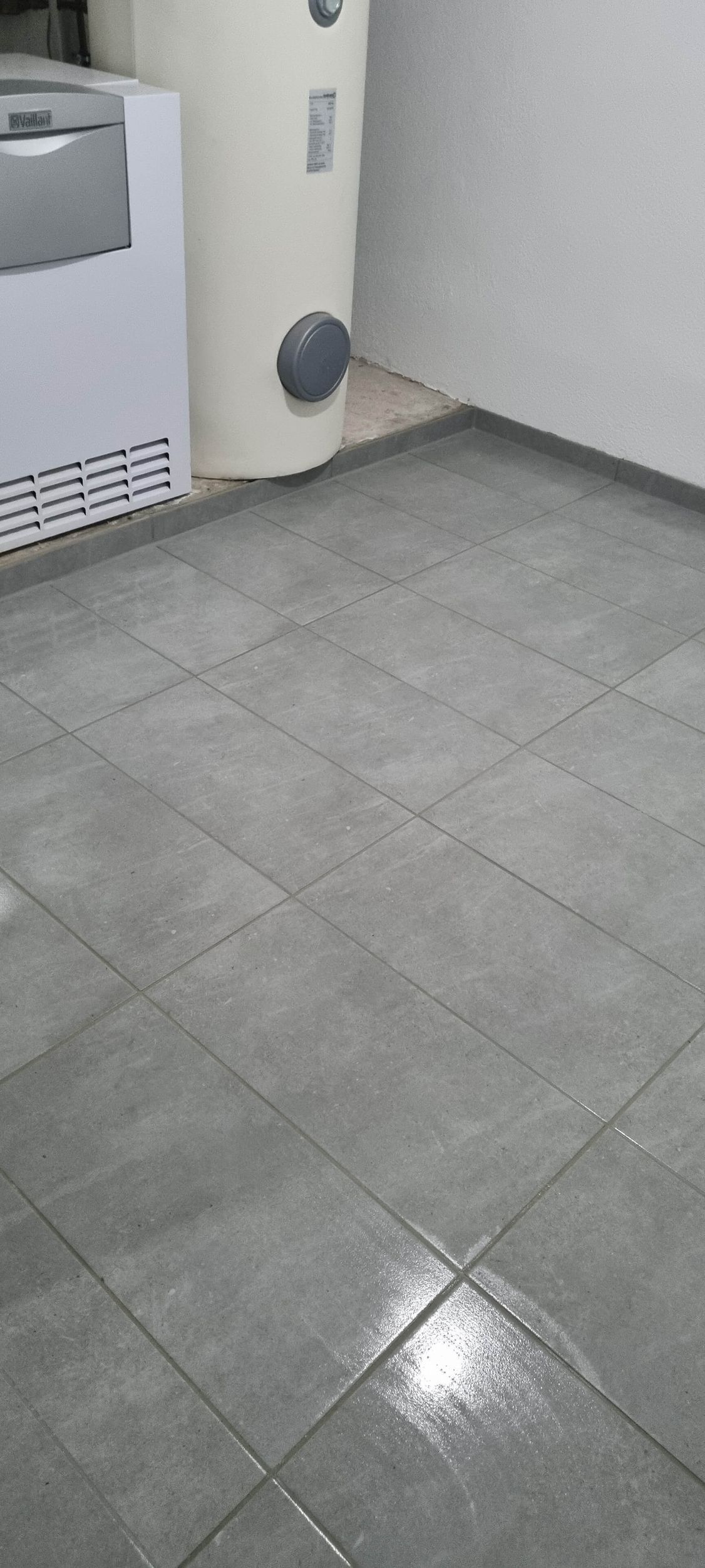 Ein gefliester Boden in einem Raum mit Waschmaschine und Trockner.