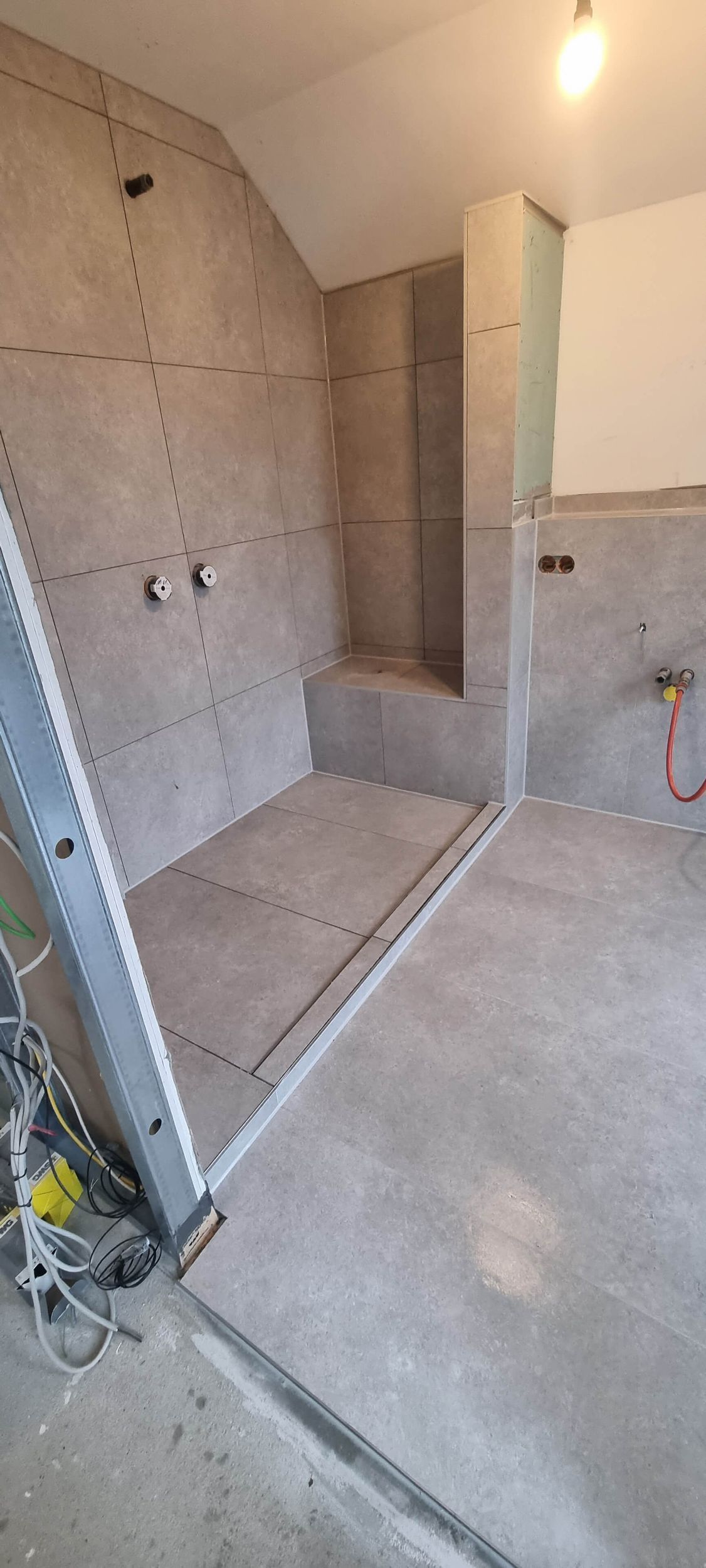 Ein im Bau befindliches Badezimmer mit ebenerdiger Dusche und Leiter.