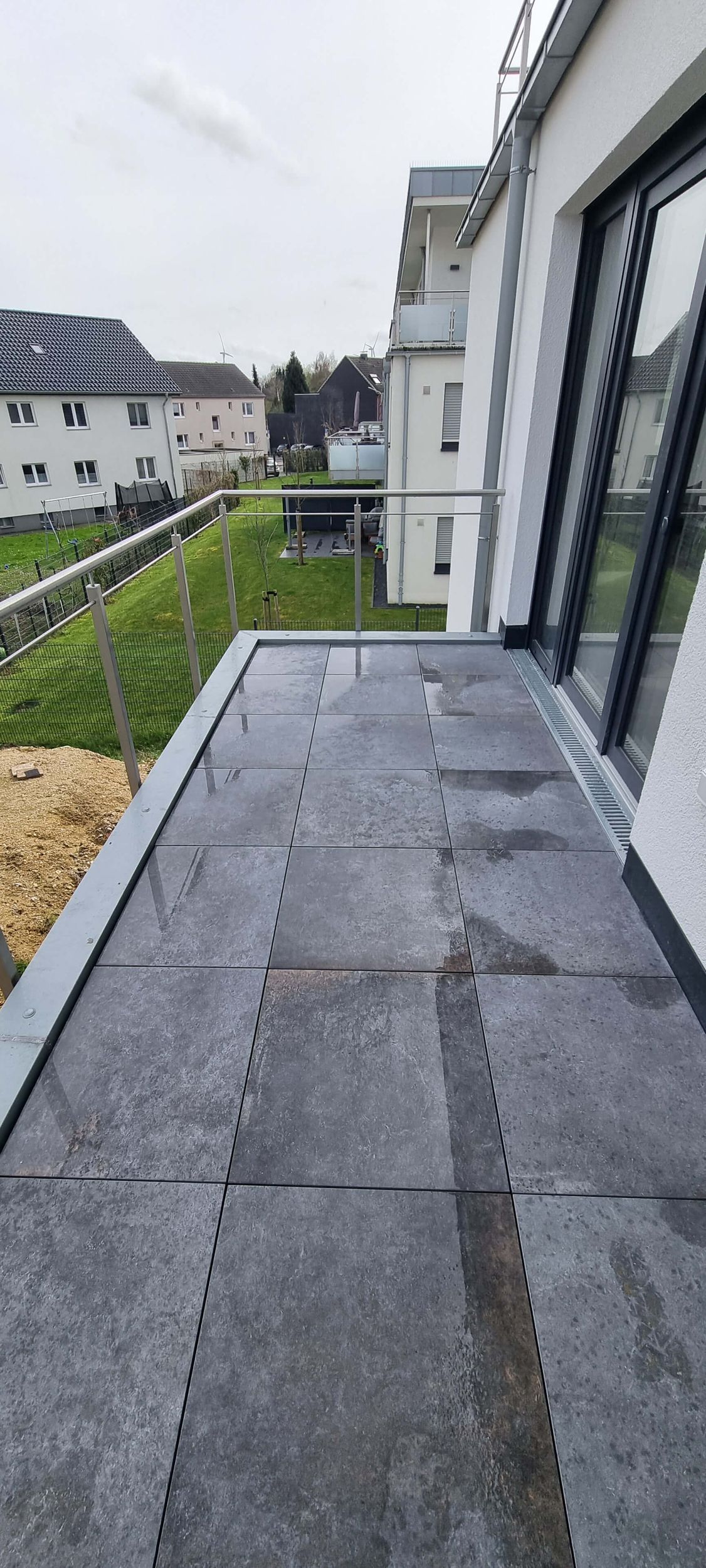 Ein Balkon mit Blick auf ein üppiges grünes Feld und ein Gebäude im Hintergrund.