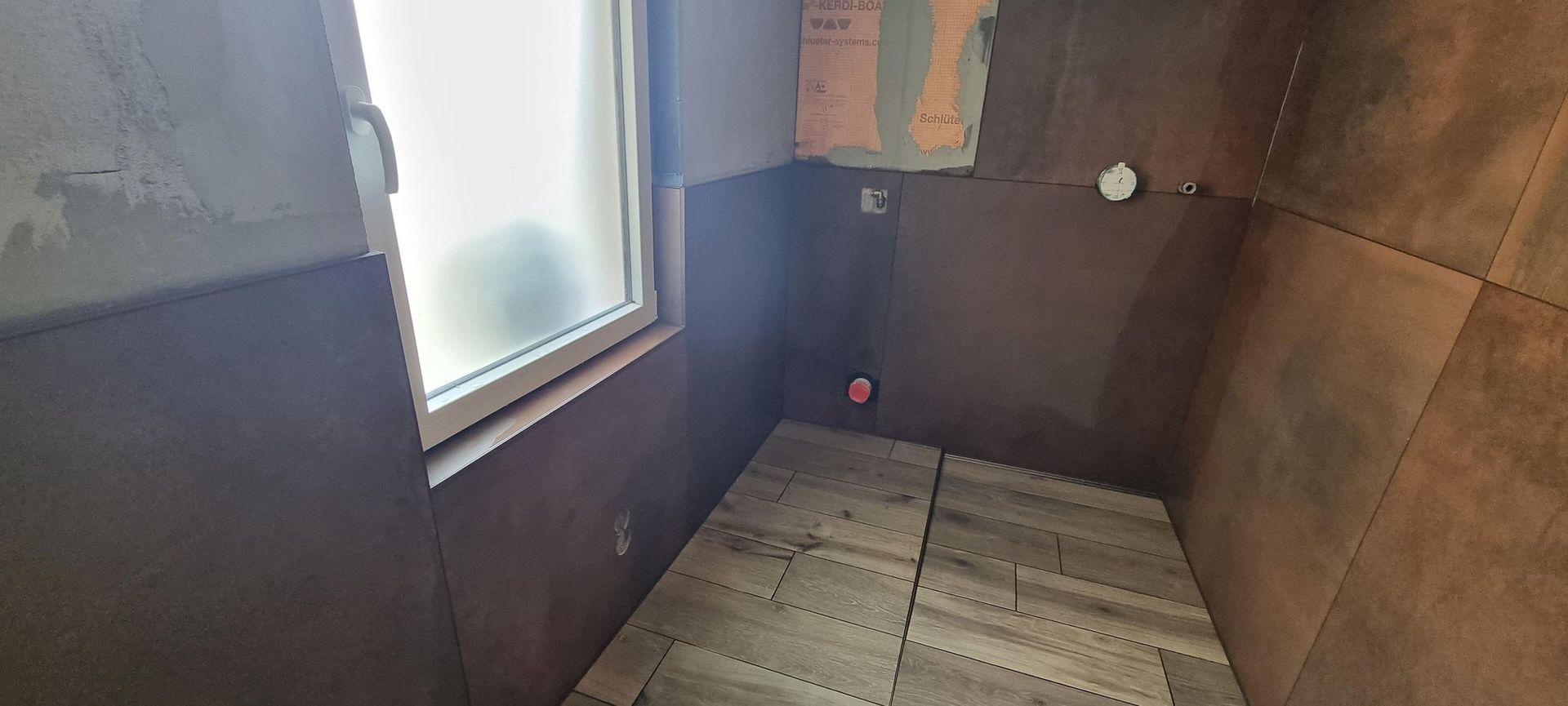 Ein im Bau befindliches Badezimmer mit Fenster und Holzboden.