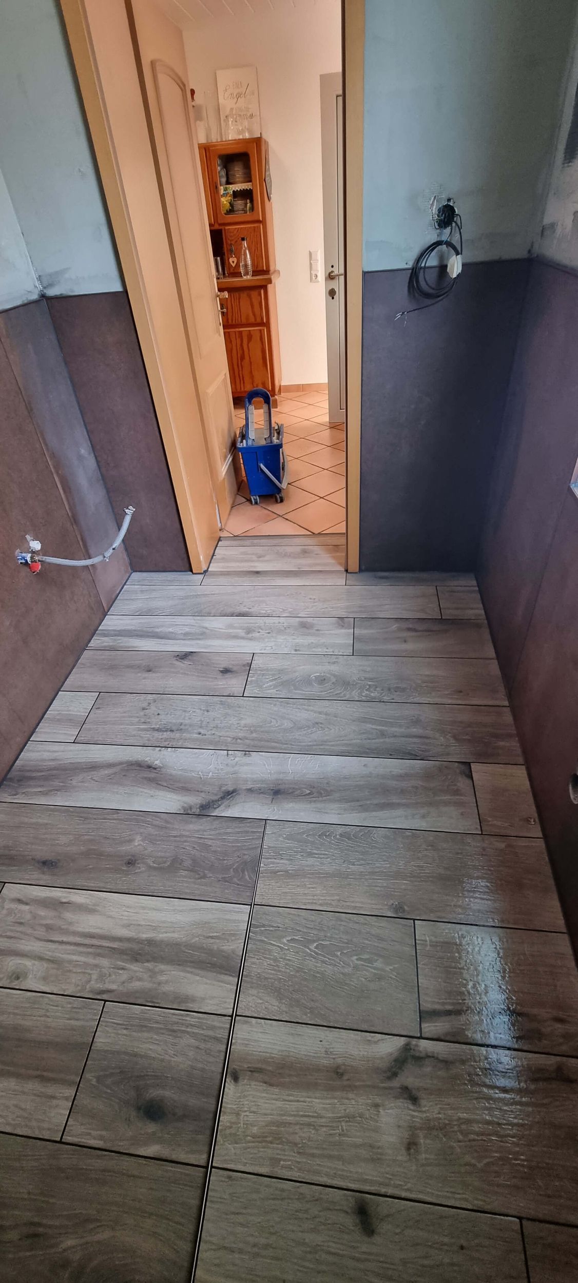 Ein Badezimmer mit Holzboden und einem Eimer auf dem Boden.