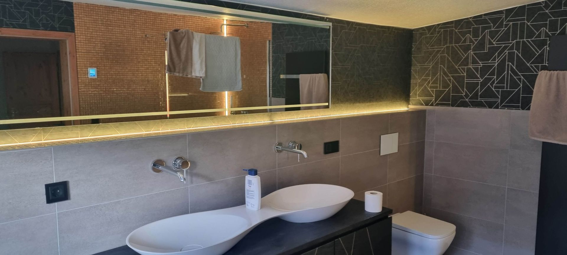 Ein Badezimmer mit zwei Waschbecken, einer Toilette und einem großen Spiegel.