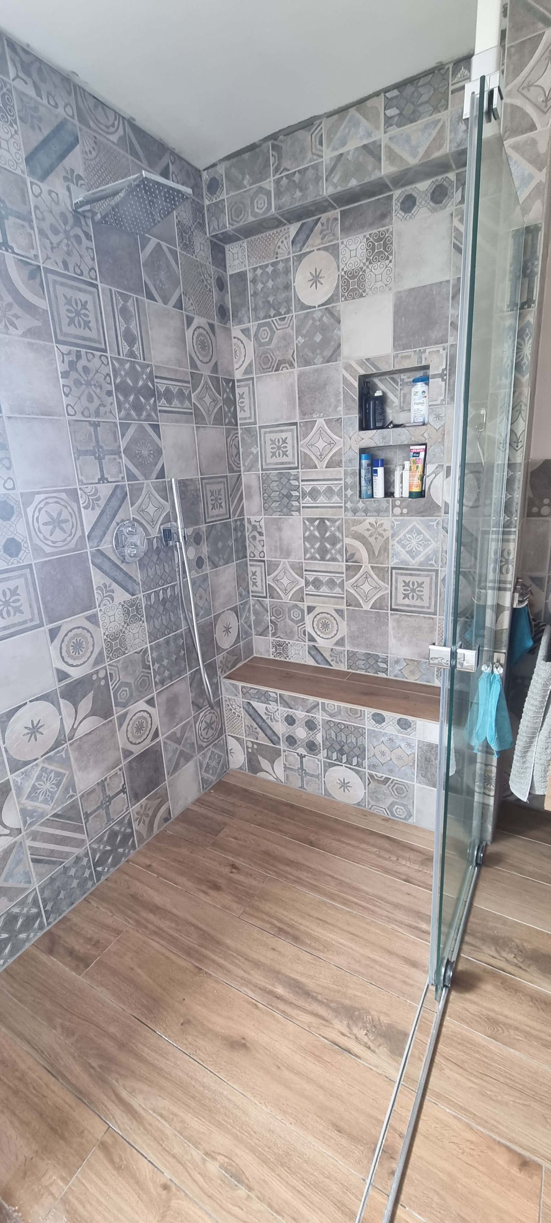 Ein Badezimmer mit ebenerdiger Dusche und Holzboden.