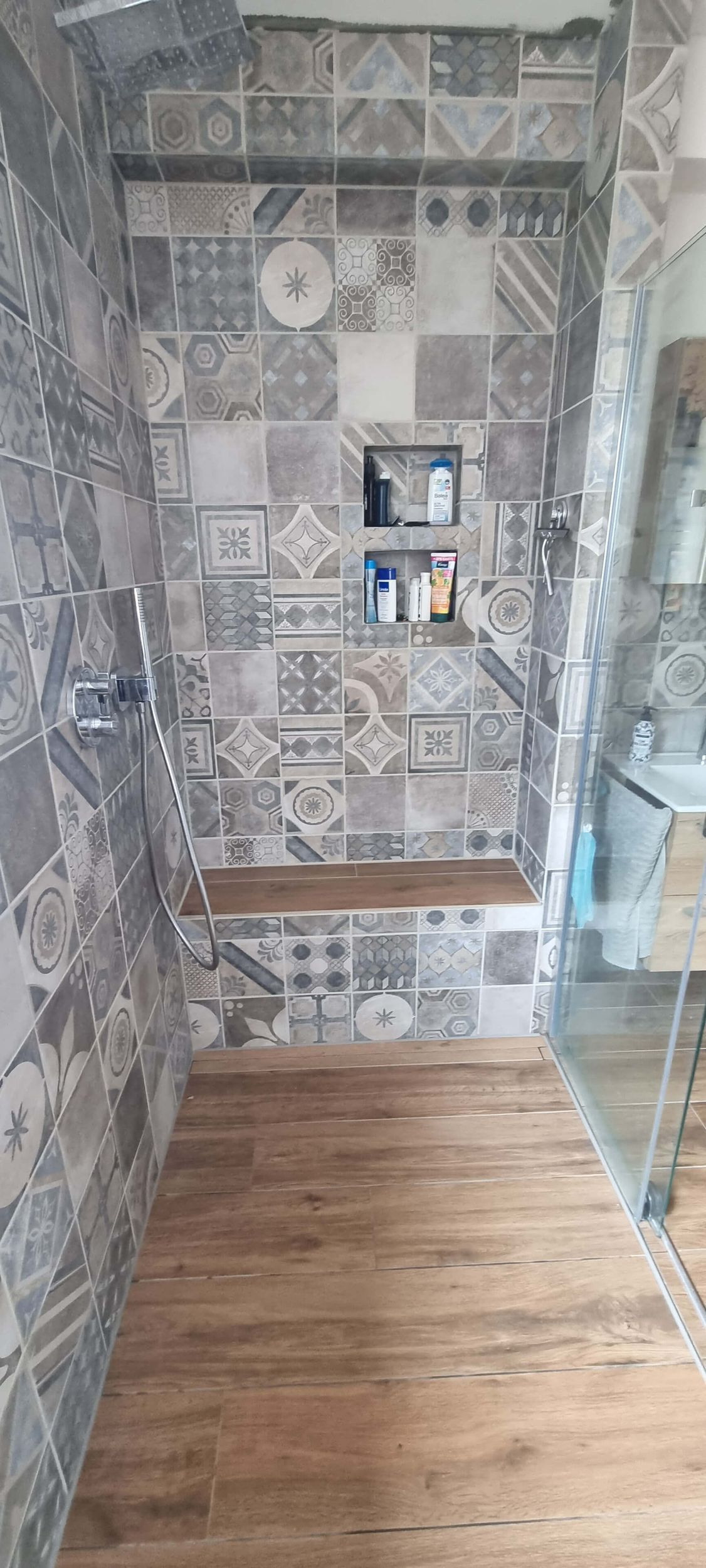 Ein Badezimmer mit ebenerdiger Dusche und Holzboden.