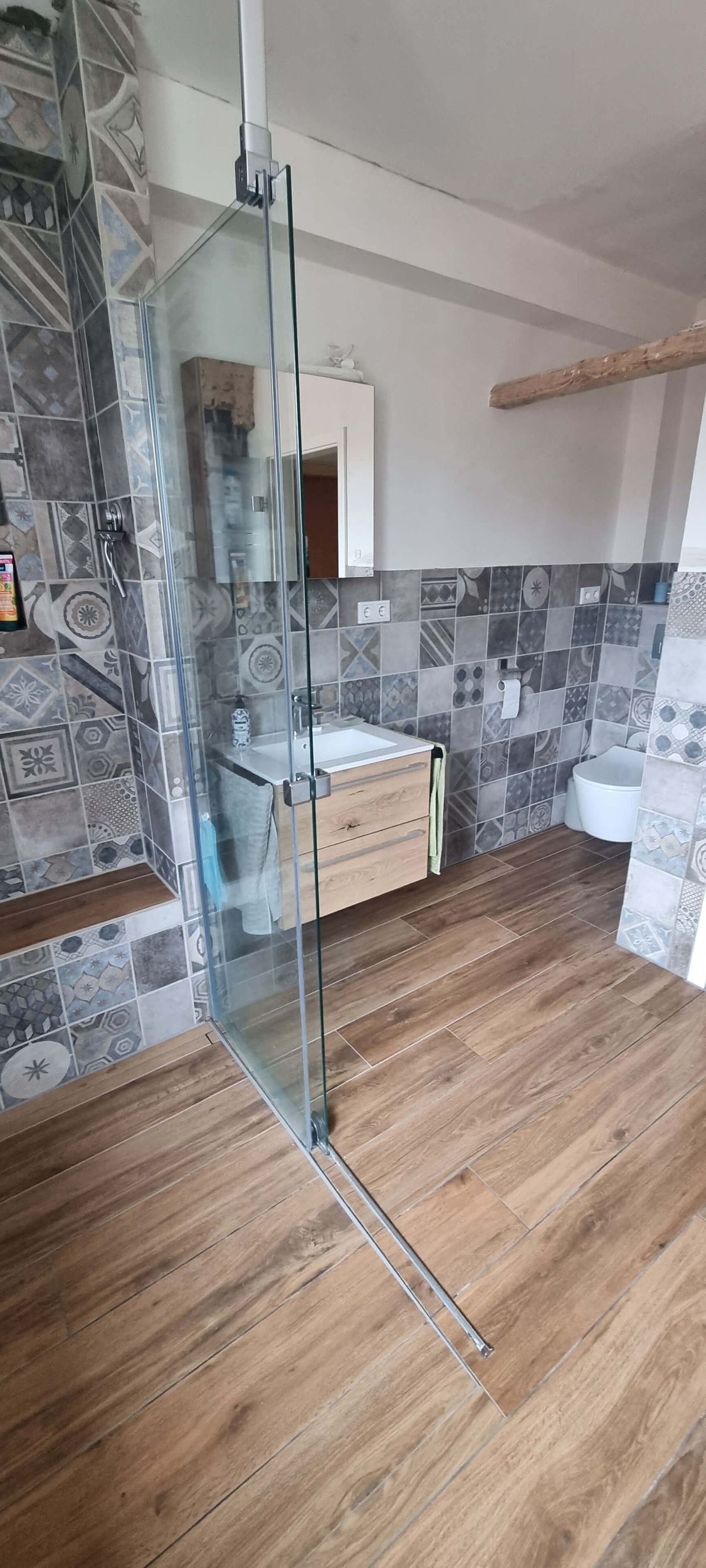 Ein Badezimmer mit ebenerdiger Dusche, Waschbecken und Toilette.