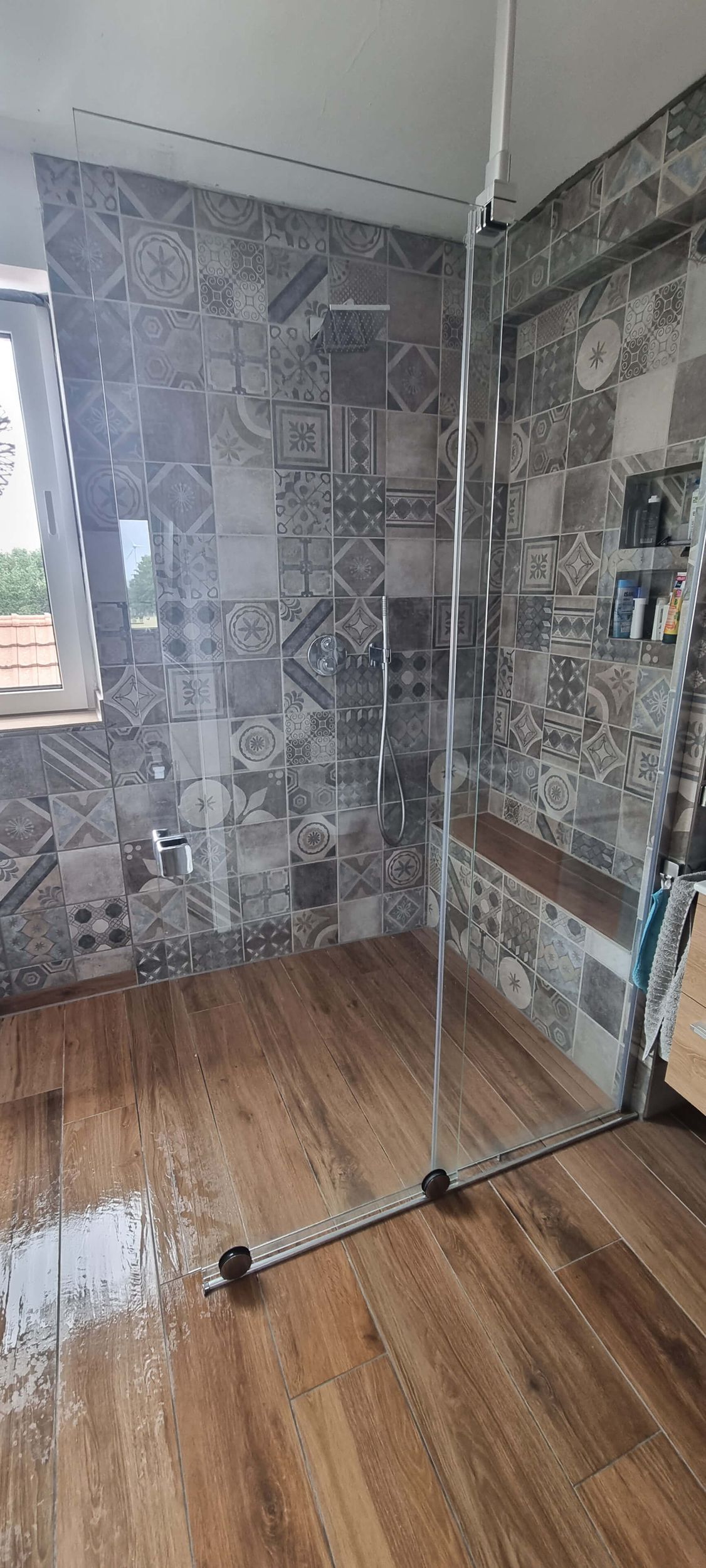 Ein Badezimmer mit ebenerdiger Dusche und Holzboden.