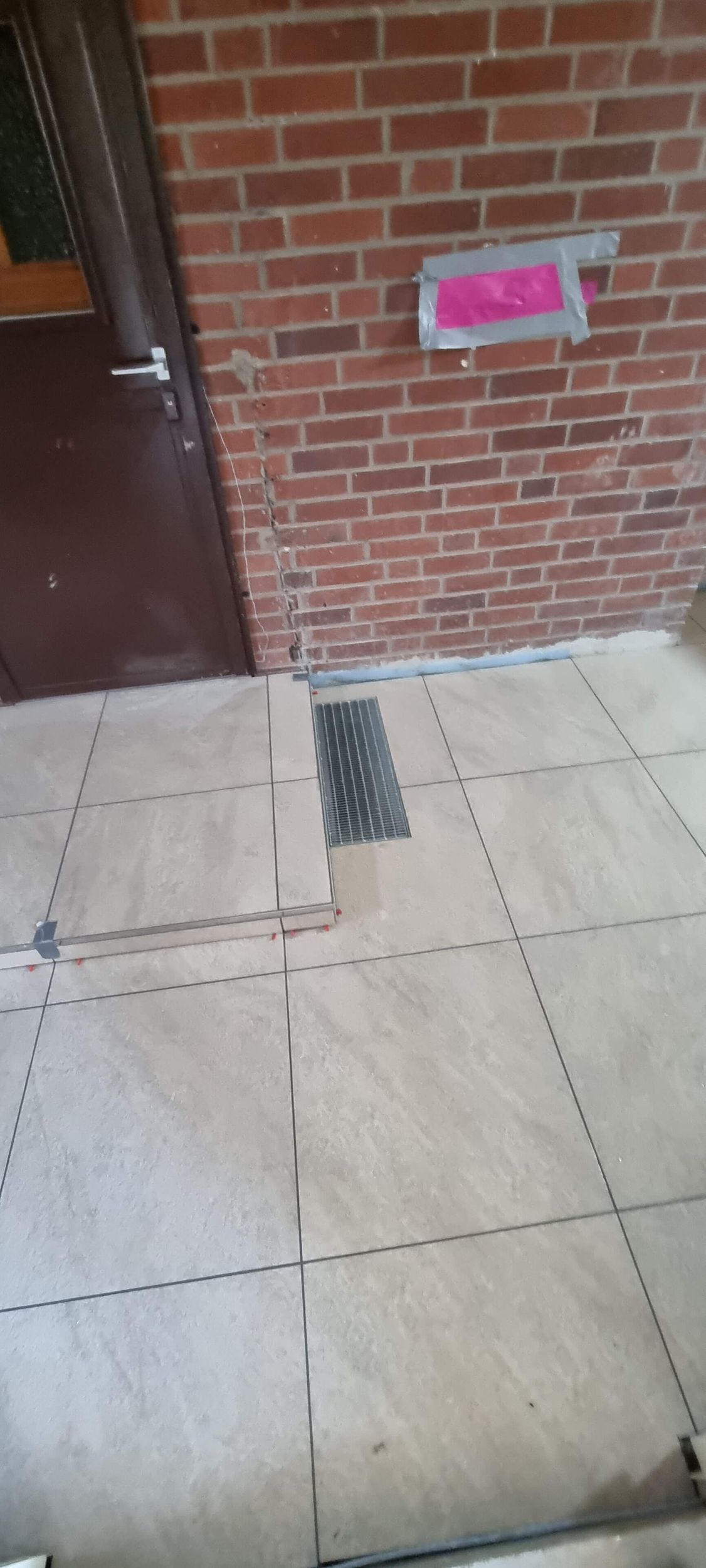 Eine Ziegelwand mit einer Tür und einem gefliesten Boden davor.