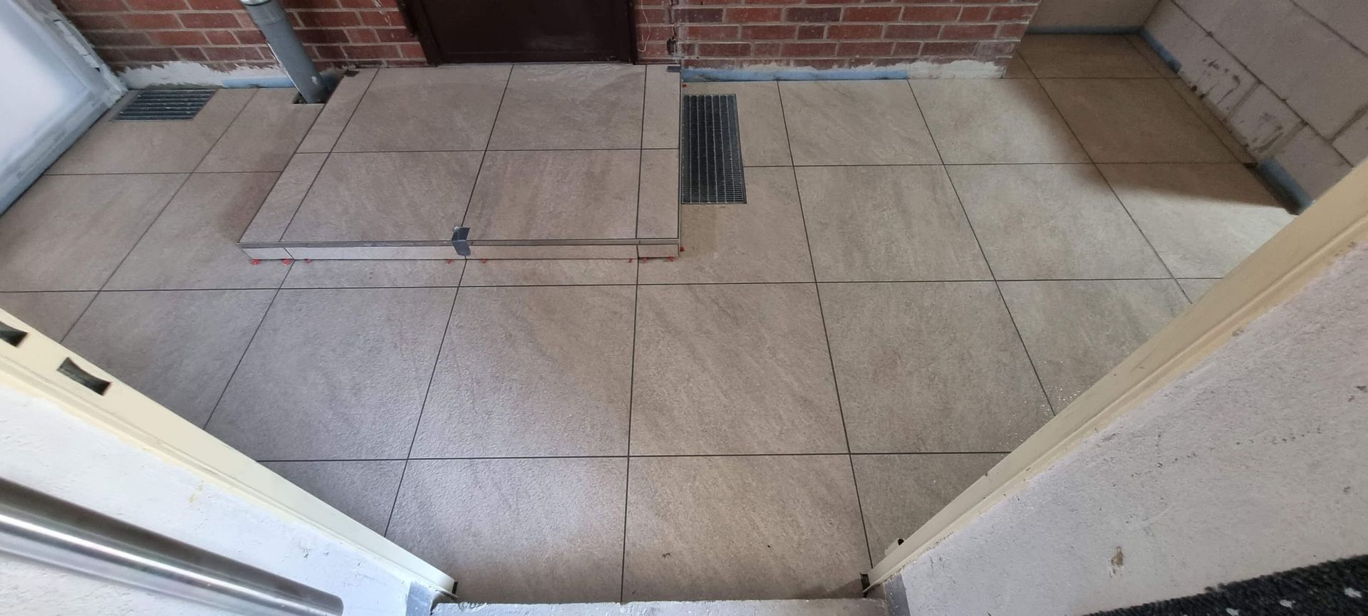 Ein gefliester Boden in einem Raum mit Treppe und Ziegelwand.