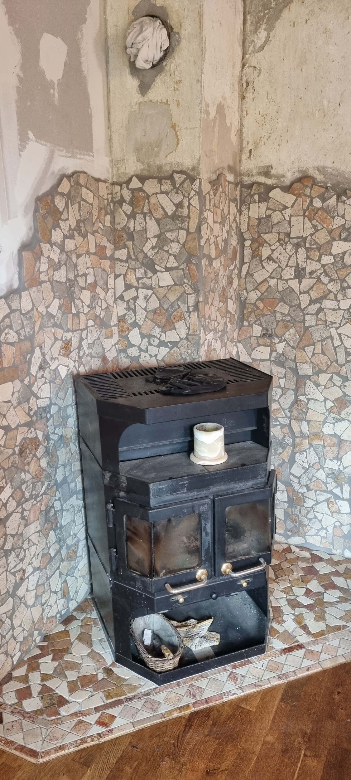 In einer Zimmerecke neben einer Backsteinwand steht ein Holzofen.