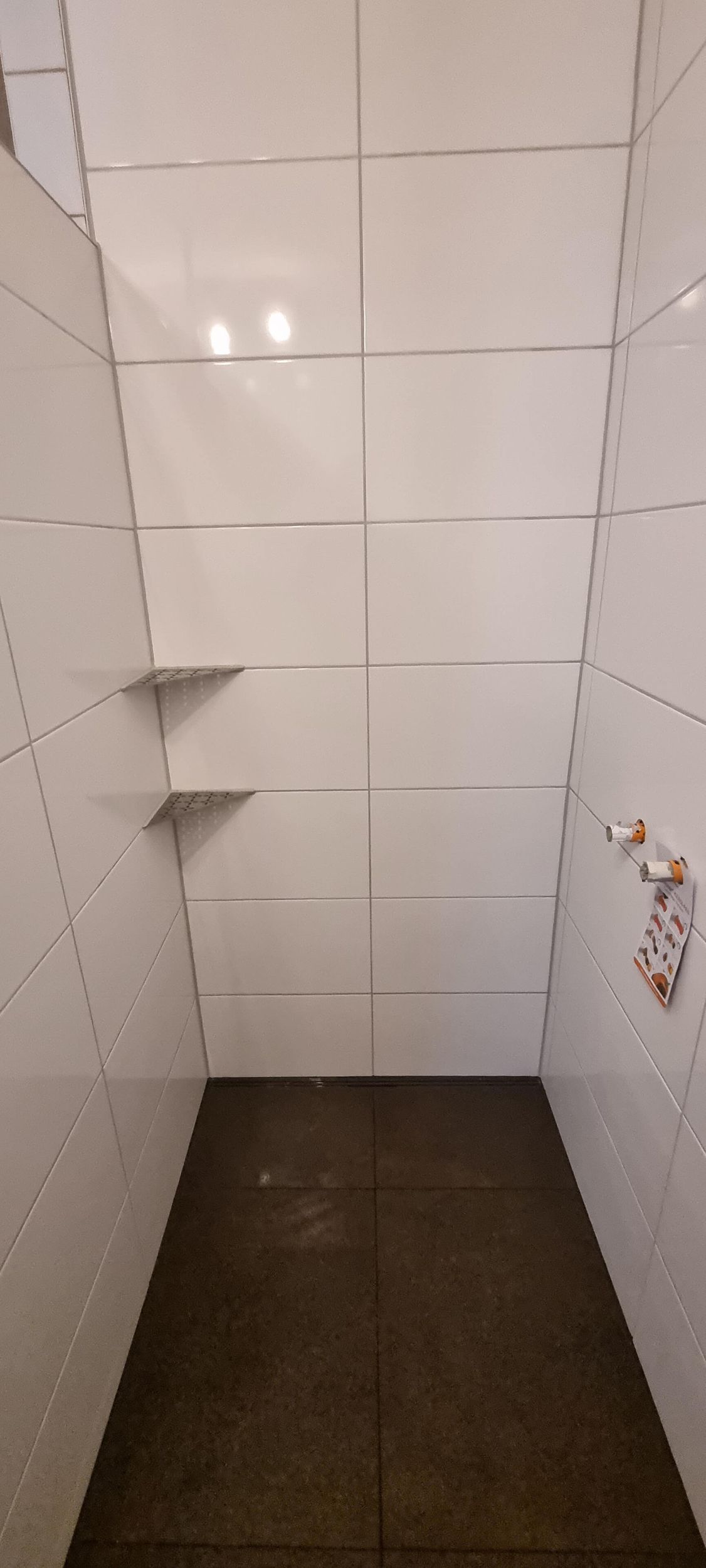 Ein Badezimmer mit weißen Fliesen und schwarzem Boden.