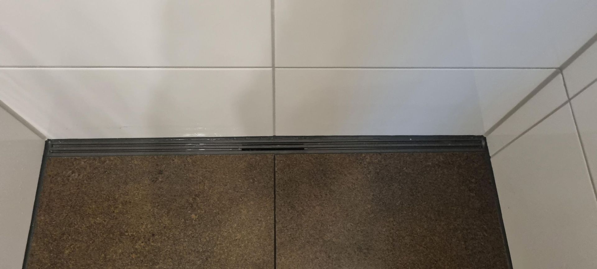 Eine Nahaufnahme eines gefliesten Bodens in einem Badezimmer mit einem Abfluss.