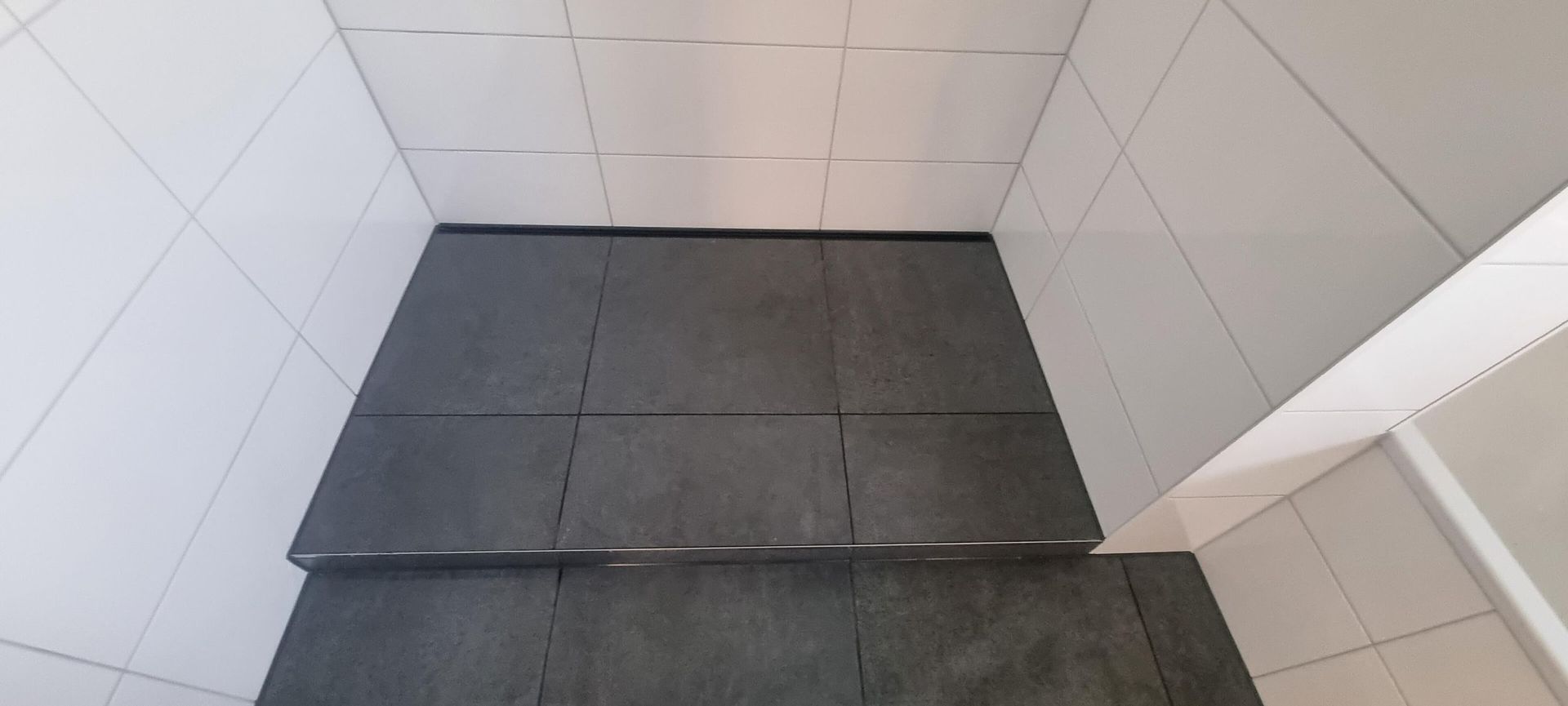 Ein Badezimmer mit schwarzen Fliesen auf dem Boden und weißen Fliesen an den Wänden.