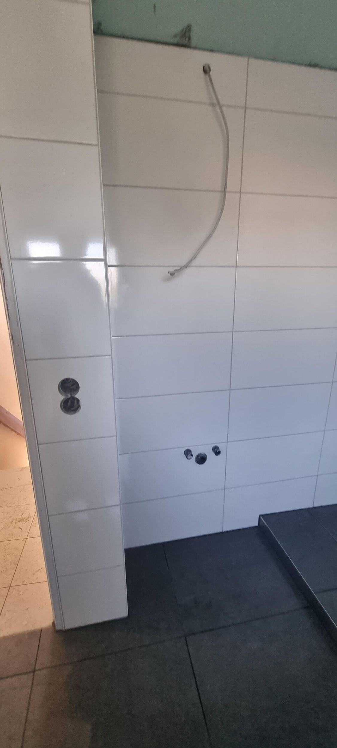 Ein Badezimmer mit weißen Fliesen und schwarzem Boden.