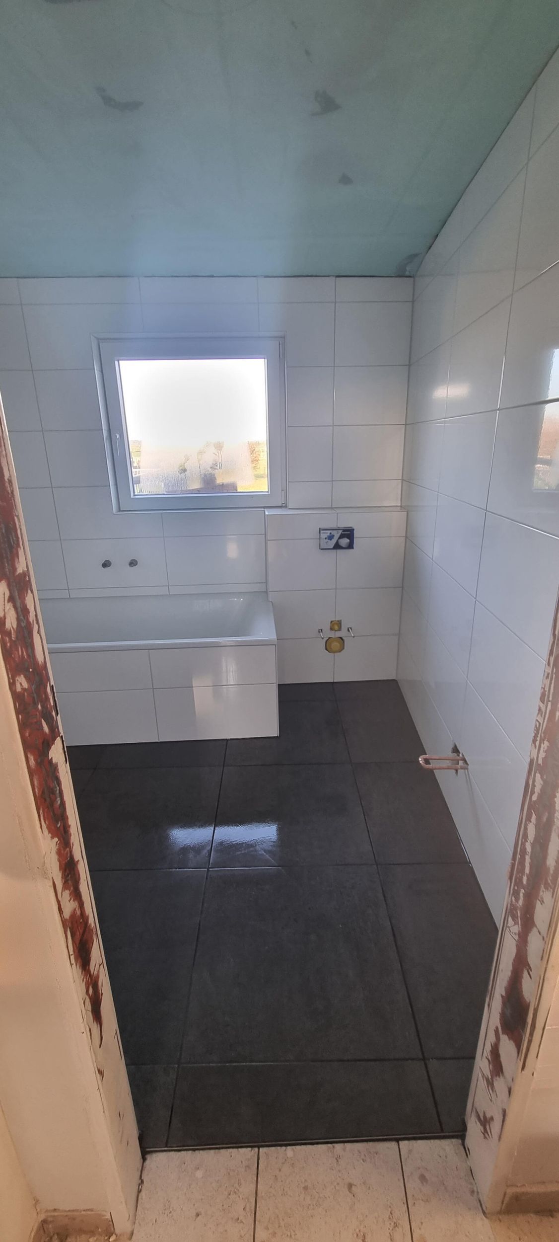 Ein im Bau befindliches Badezimmer mit Waschbecken und Fenster.