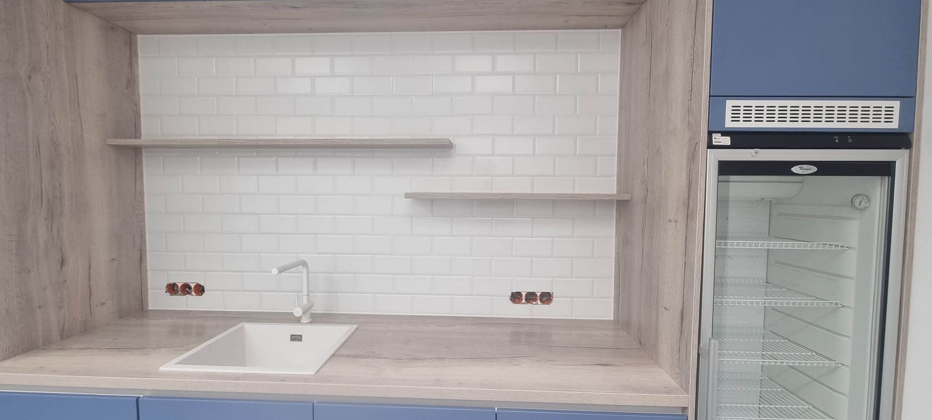 Eine Küche mit Spüle, Kühlschrank und Regalen.