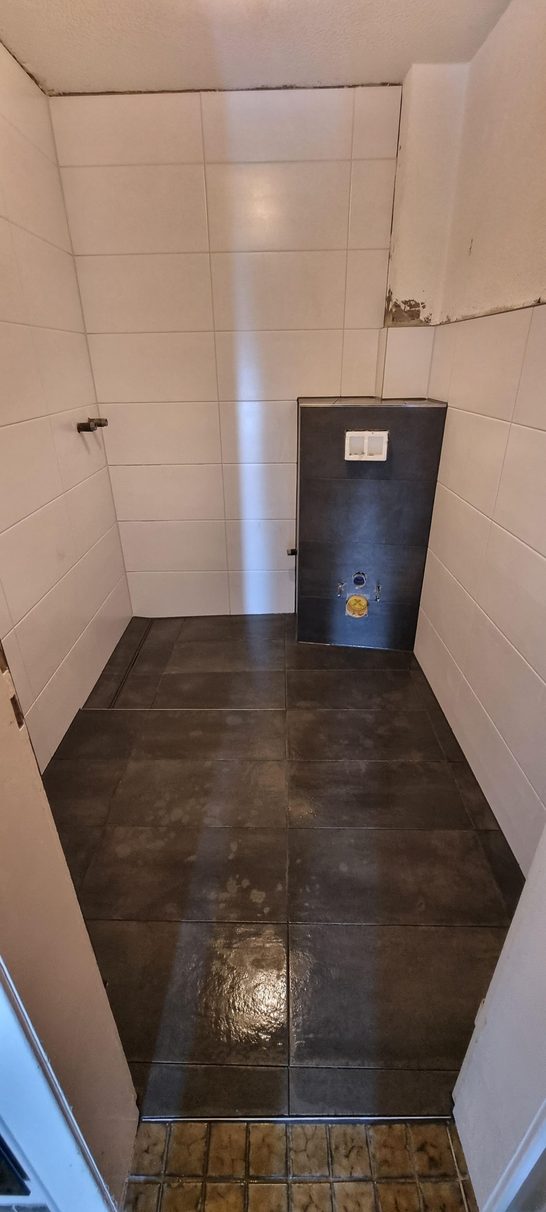 Ein Badezimmer mit schwarzem Fliesenboden und weißen Fliesen an der Wand.