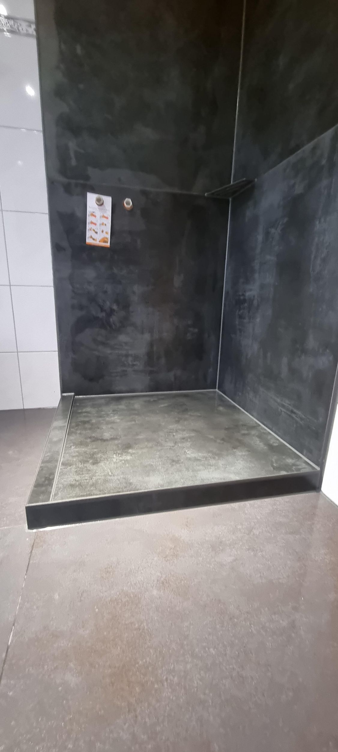 Ein Badezimmer mit ebenerdiger Dusche und einer schwarzen Wand.