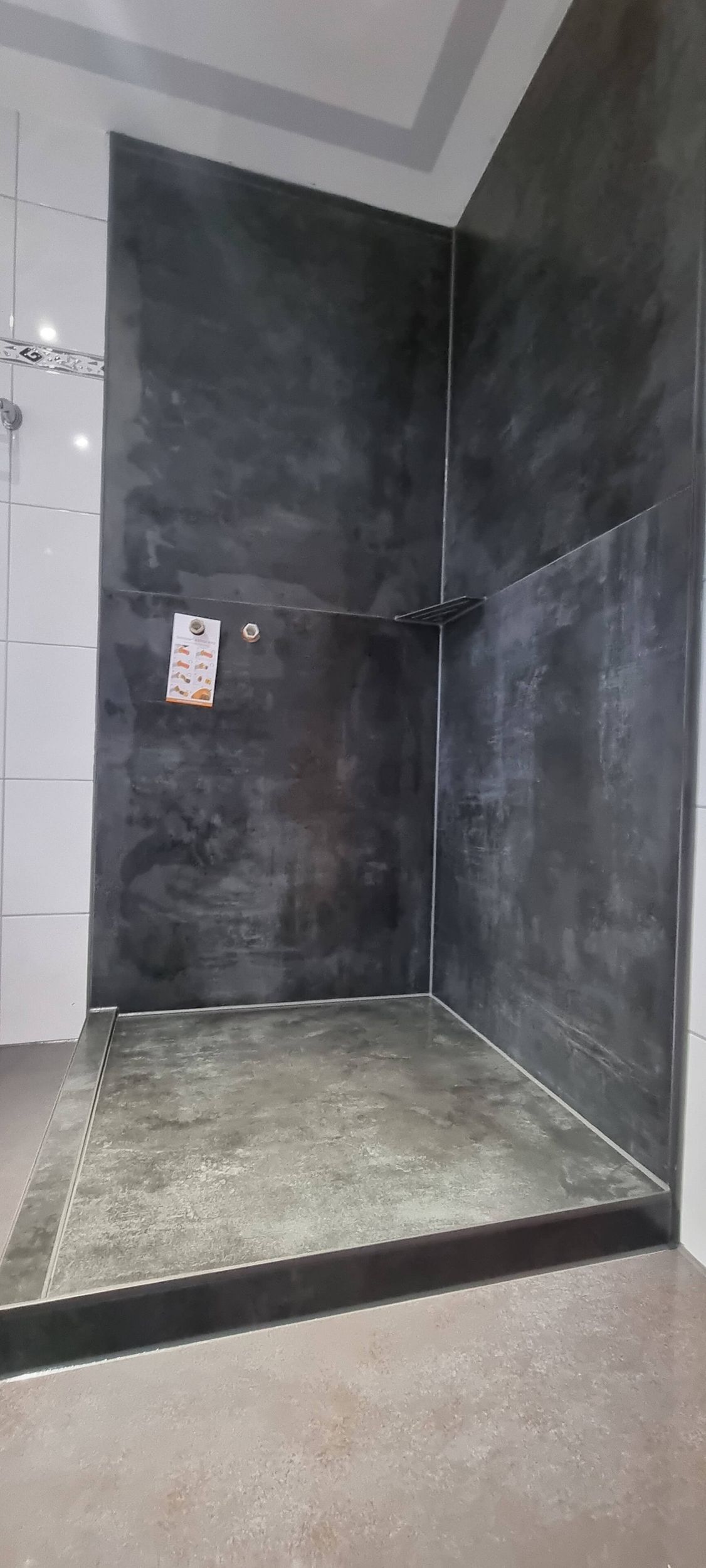 Ein Badezimmer mit ebenerdiger Dusche und einer schwarzen Wand.