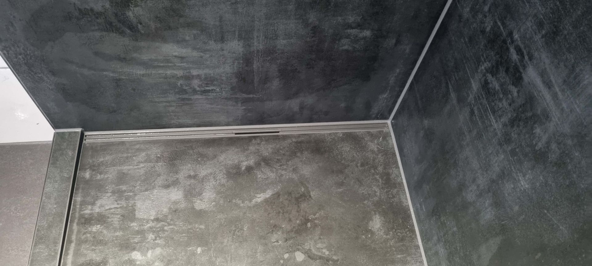 Eine Badezimmerecke mit einem Abfluss im Boden.