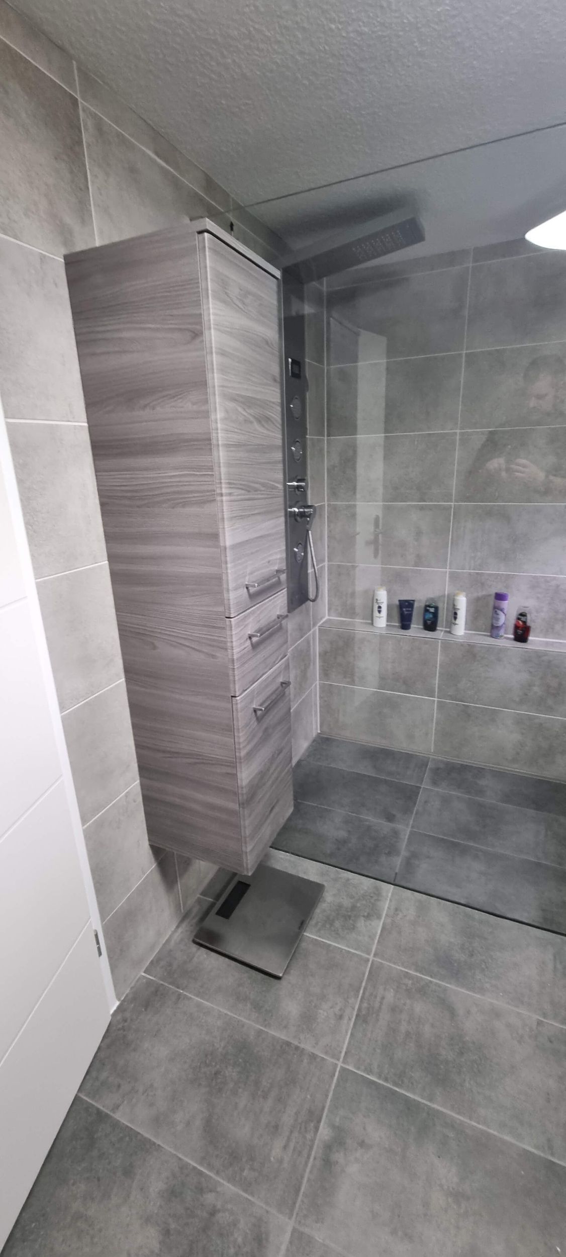 Ein Badezimmer mit grauem Fliesenboden und einem Holzschrank.