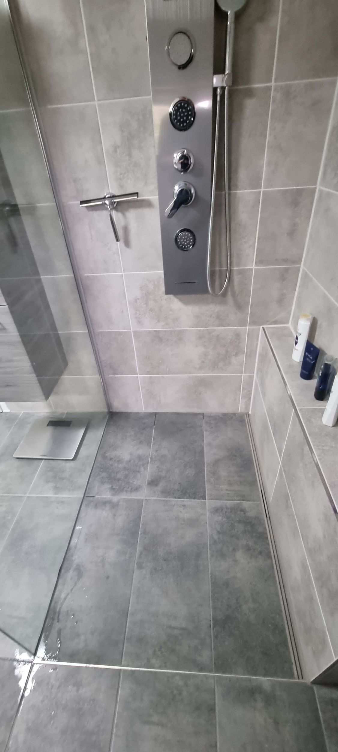 Ein Badezimmer mit ebenerdiger Dusche und Duschkopf.