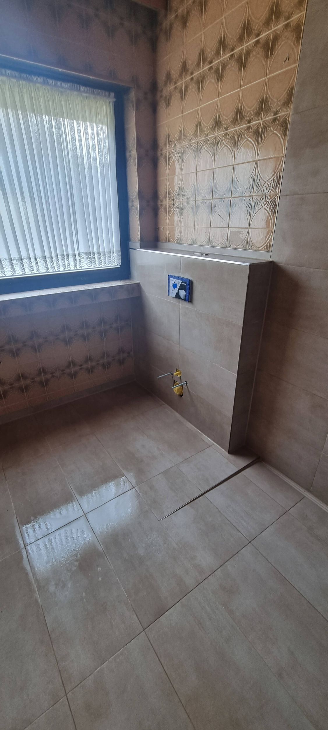 Ein Badezimmer mit gefliestem Boden und Fenster.