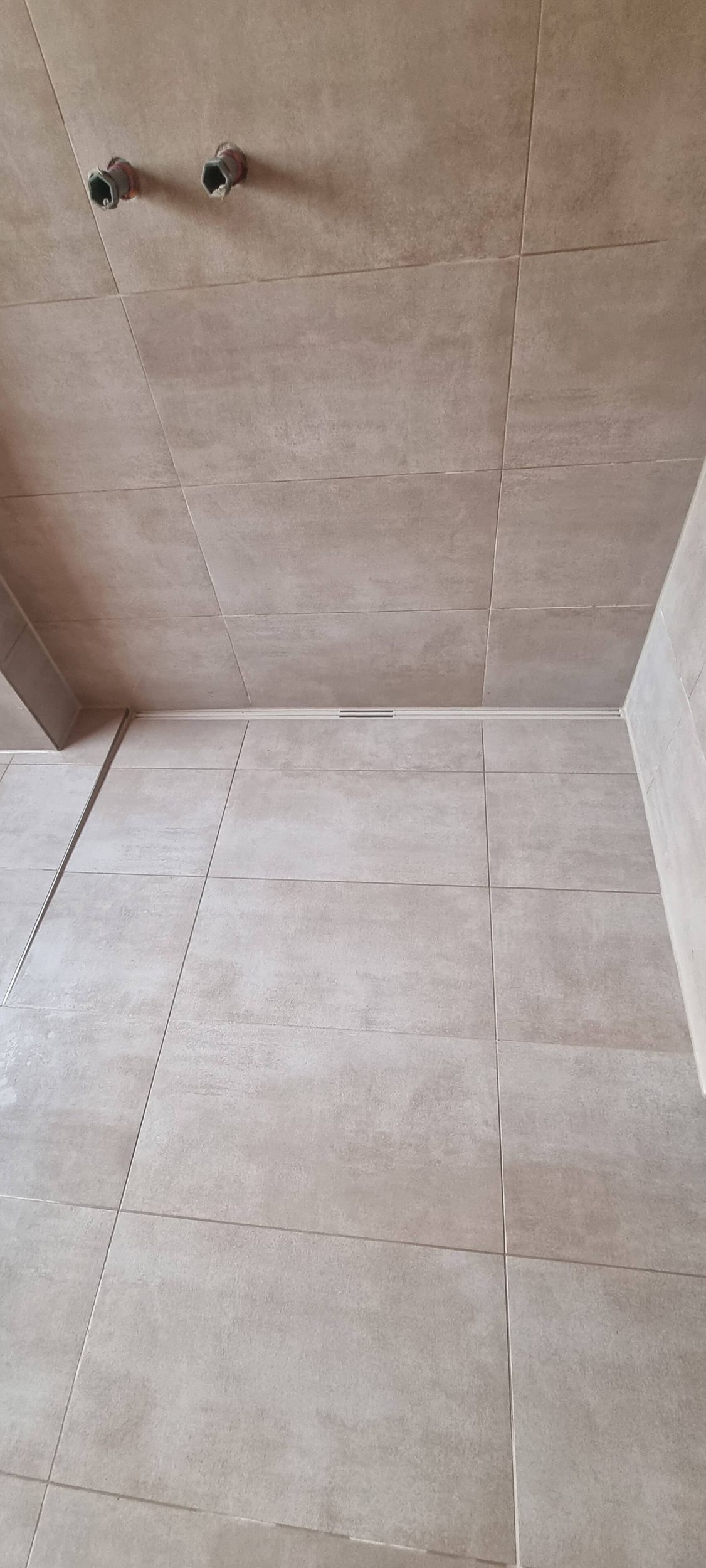 Ein Badezimmer mit gefliestem Boden und Duschkopf.