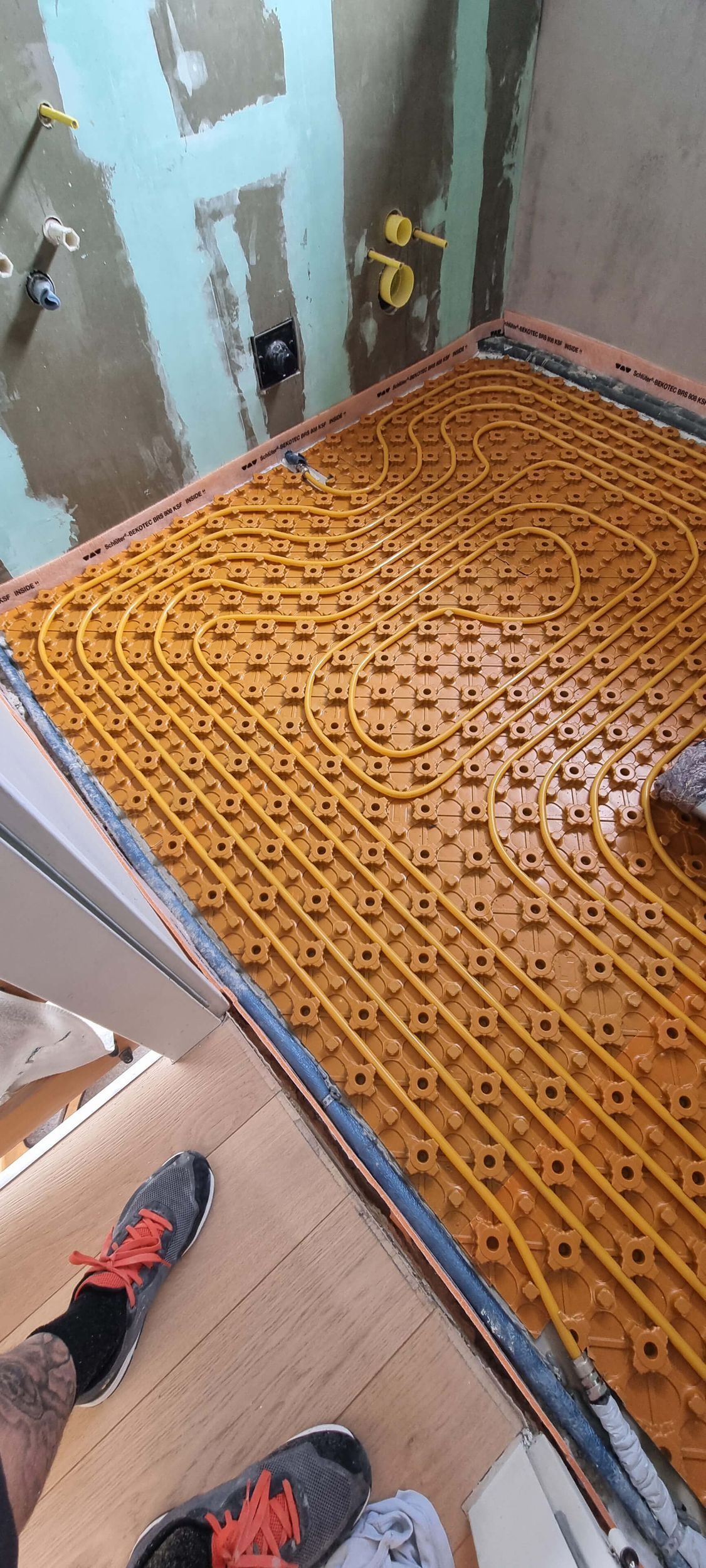 Eine Person verlegt einen Fliesenboden in einem Badezimmer.