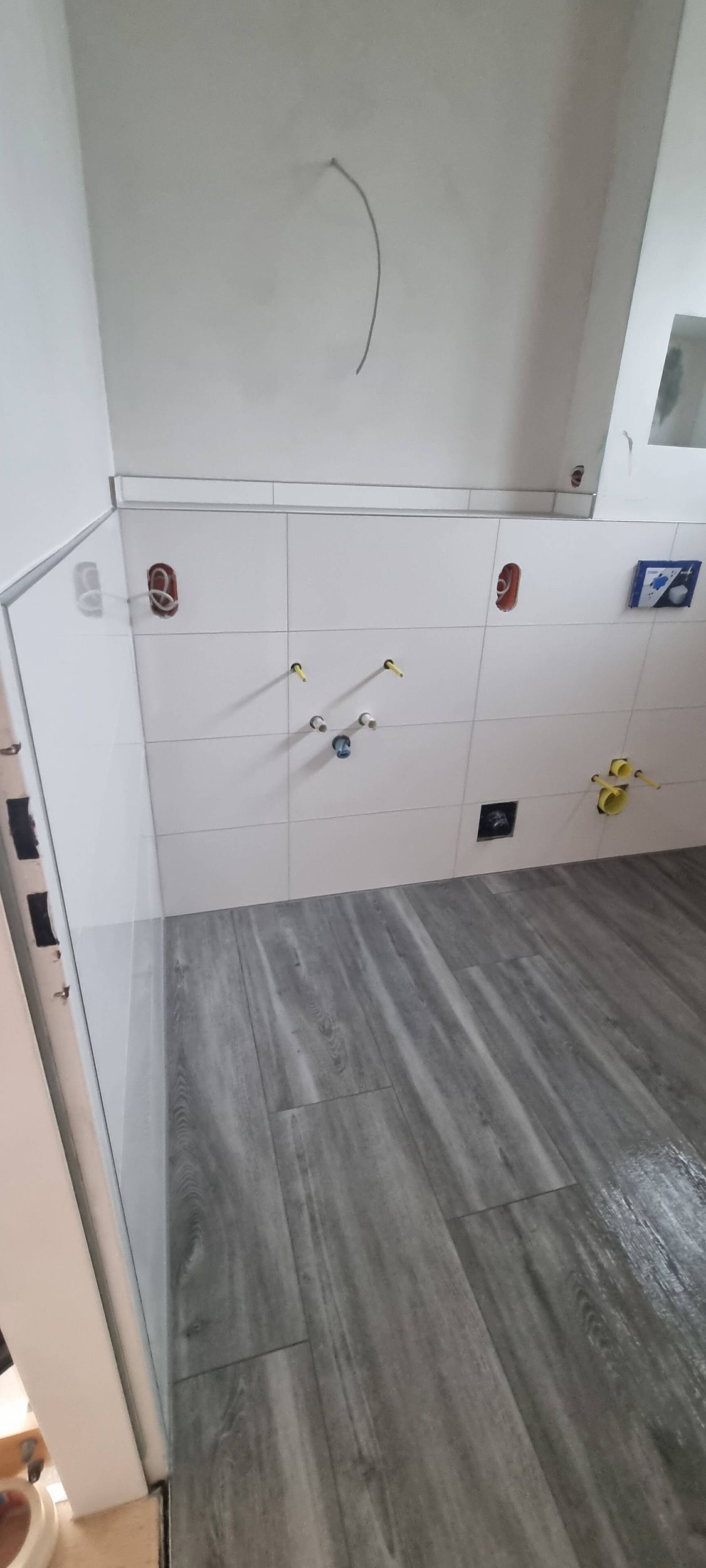 Ein Badezimmer mit Holzboden und weißen Fliesen.