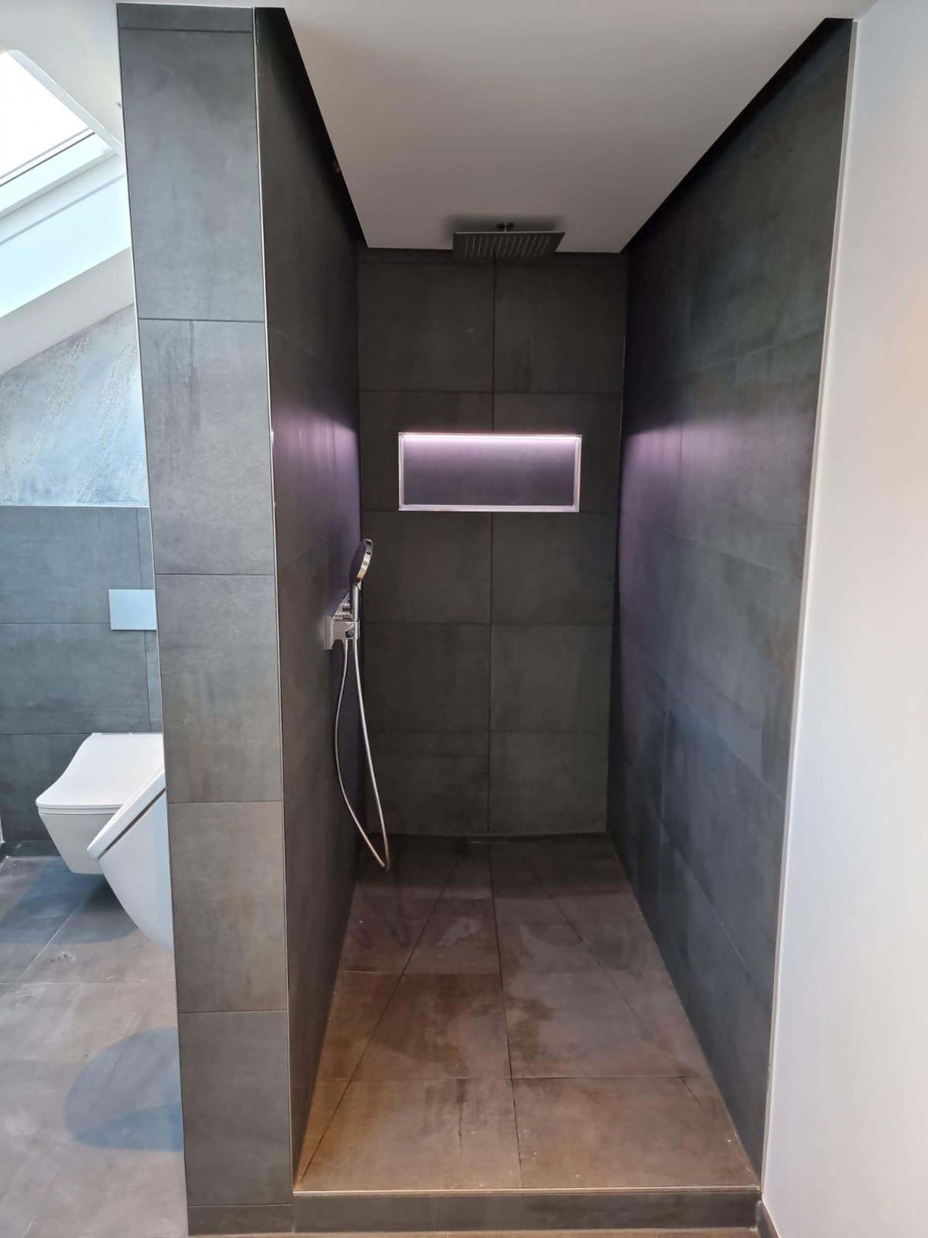 Ein Badezimmer mit ebenerdiger Dusche und Toilette