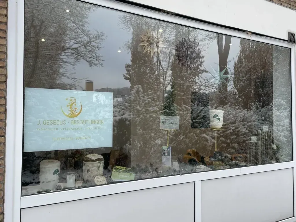 Schaufensterauslage mit Schild, Produkten und verschneitem Hintergrund im Freien.