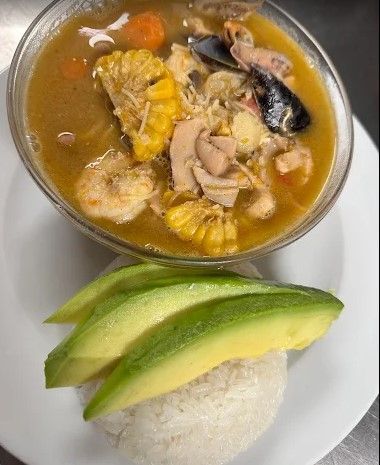 Bol de guiso de mariscos con arroz y rodajas de aguacate en un plato.
