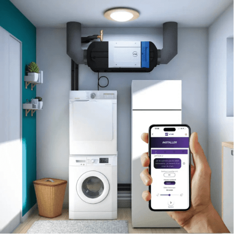 Une personne utilise un smartphone pour contrôler un système de ventilation dans une buanderie équipée d'appareils électroménagers, d'un plafonnier et de conduits d'aération.