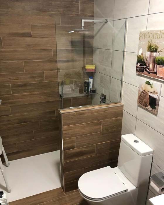 Un baño con inodoro, ducha y baldosas de madera.