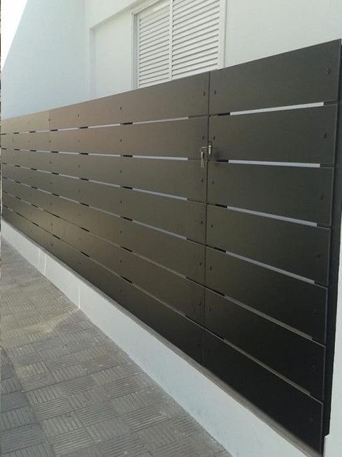 Una valla de madera negra a lo largo del costado de un edificio.