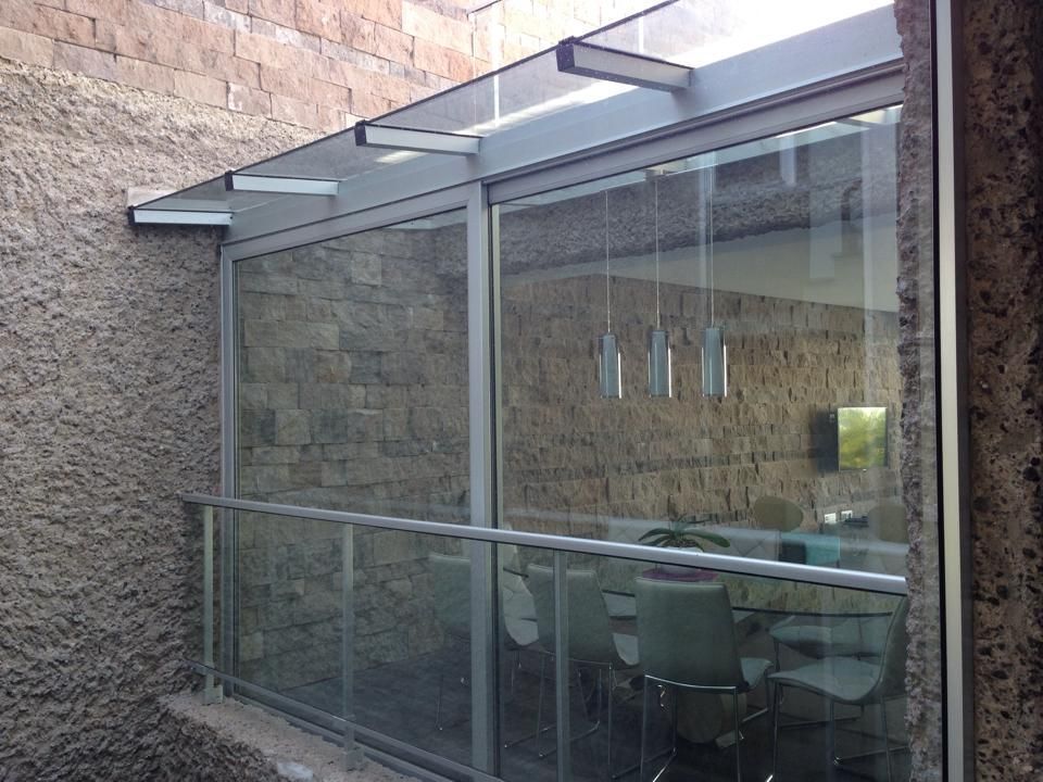 Un comedor con una mesa y sillas detrás de una pared de cristal.