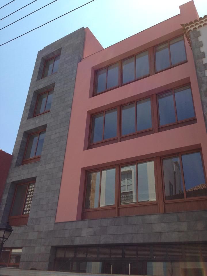Un edificio con muchas ventanas y una fachada rosa.
