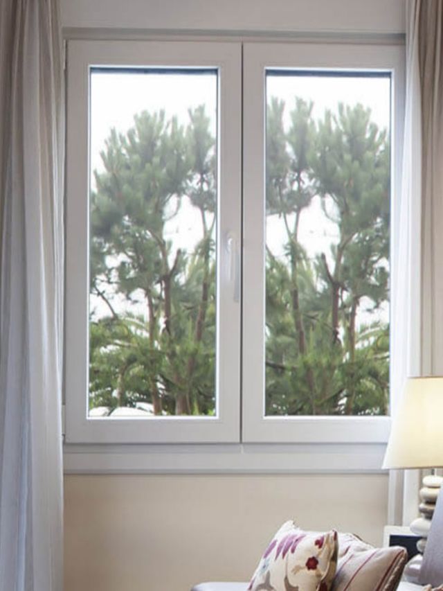 Una sala de estar con un sofá y una ventana con árboles al fondo.