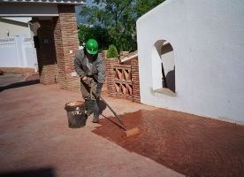 Un hombre está pintando un camino de entrada con una escoba.