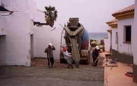 Un grupo de trabajadores de la construcción está parado frente a un camión hormigonera.