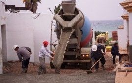 Un grupo de trabajadores de la construcción está trabajando delante de un camión hormigonera.