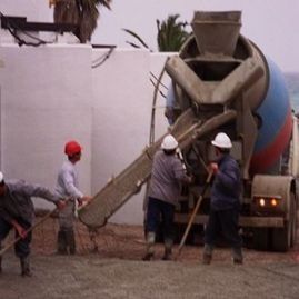 Un grupo de trabajadores de la construcción de pie frente a una hormigonera