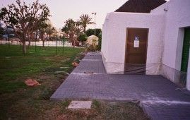 Un edificio blanco con una puerta en medio de un parque.