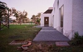 Un edificio blanco con una pasarela de hormigón que conduce a él.