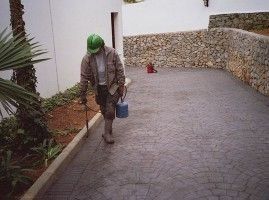 Un hombre que lleva un casco verde camina por un camino de entrada.